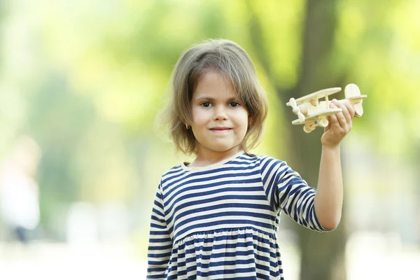 Маленькая девочка играет с деревянным самолетом — стоковое фото