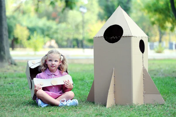 Little girl sitting near carton rocket — Stock Photo, Image