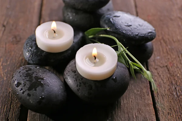 Alight candles on pebbles on wooden background, close up — Stock Photo, Image