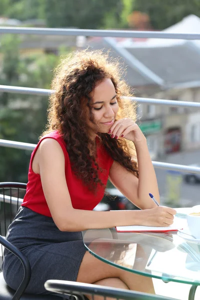 Femme souriante en robe rouge fait la notation — Photo