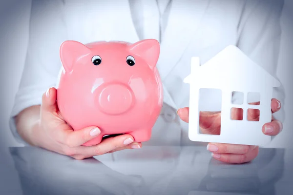 Mujer holding casa y alcancía — Foto de Stock