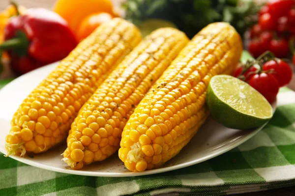Appetizing grilled corn served with vegetables and green plaid pattern napkin — Stock Photo, Image