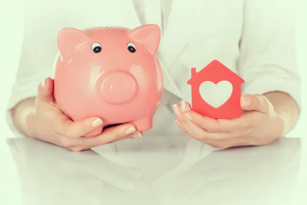 Mujer holding casa y alcancía — Foto de Stock