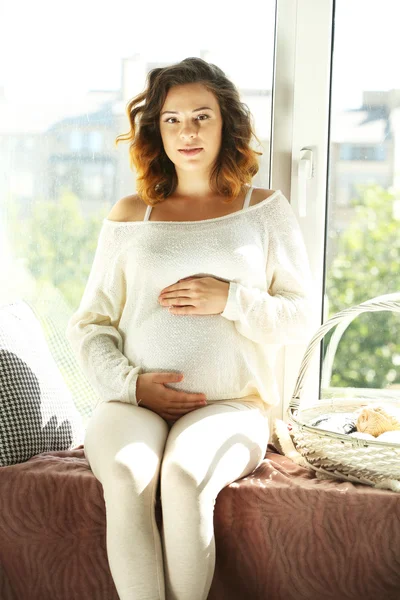 Pencere tahta üzerinde oturan hamile kadın — Stok fotoğraf
