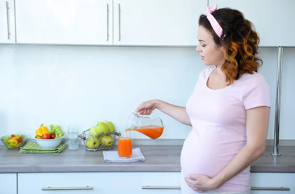 Беременная женщина наливает сок в стакан — стоковое фото
