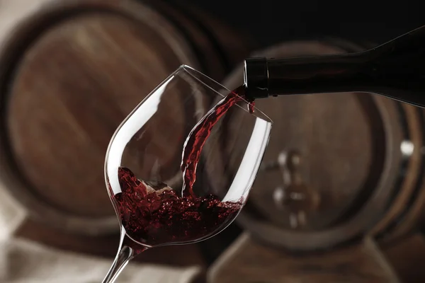 Pouring red wine from bottle into glass — Stock Photo, Image