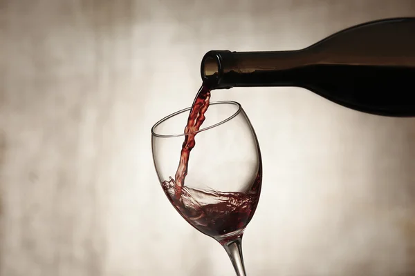Pouring red wine from bottle into glass — Stock Photo, Image