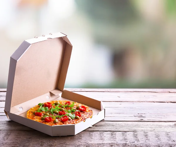 Pizza in box on wooden table