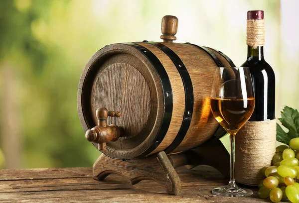 Uva branca e vermelha com garrafa de vinho perto do barril — Fotografia de Stock