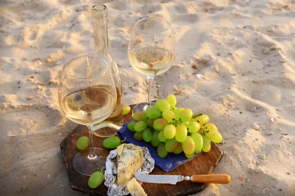 Composição romântica de vinho branco e uva na praia de areia — Fotografia de Stock