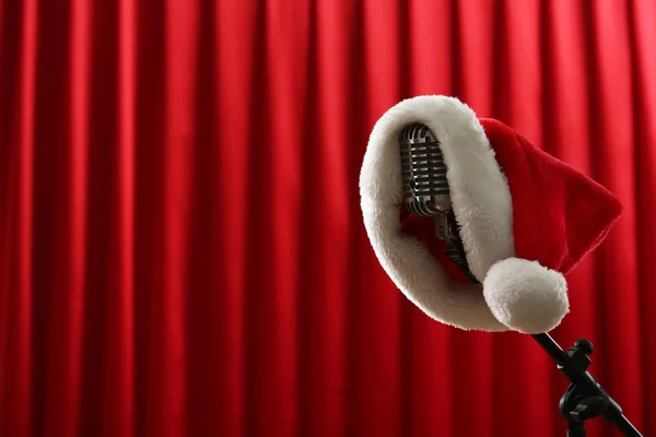 Micrófono vintage con sombrero de Navidad sobre fondo de cortina roja —  Fotos de Stock