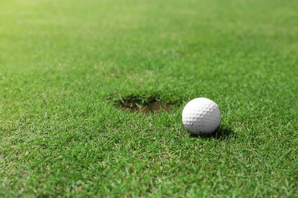 Мяч для гольфа на краю чашки — стоковое фото