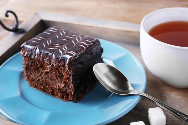 Cake on blue plate with cup of tea — Stock Photo, Image