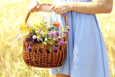Kadın holding sepeti ile kır çiçekleri 