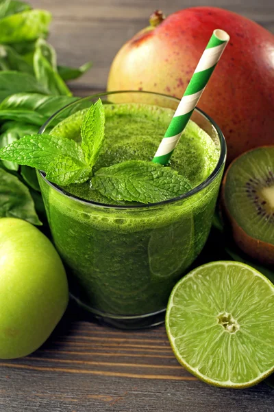 Green healthy juice with fruits and herbs on wooden table close up — Stock Photo, Image