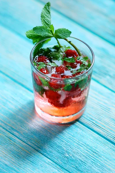 Glass of cold refreshing summer drink with berries and ice cubes on table close up — Stock Photo, Image