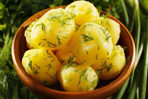 Вареный картофель с зеленью в миске на столе вблизи — стоковое фото