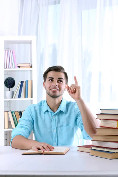 Young man reading book at table — Stock Photo, Image