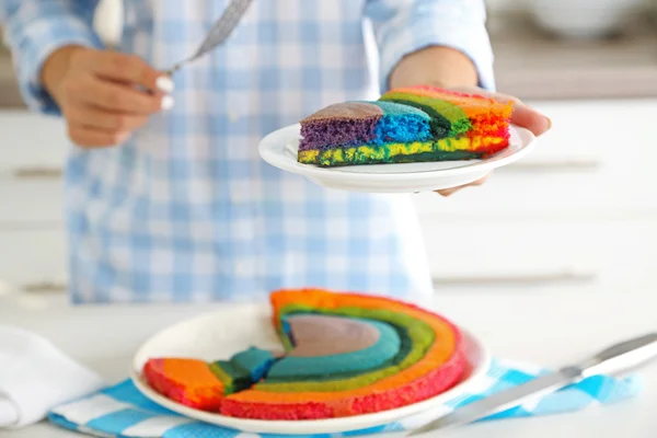 Kobieta trzyma płytki z rainbow cake — Zdjęcie stockowe