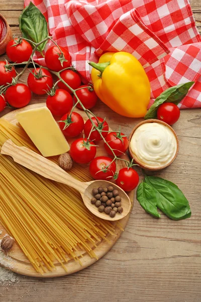 Těstoviny špagety s rajčaty, sýrem a bazalkou na rustikální dřevěné pozadí — Stock fotografie