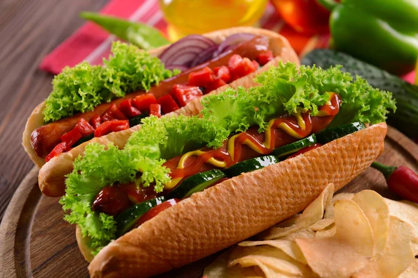 Hot dogs et légumes sur planche à découper en bois — Photo