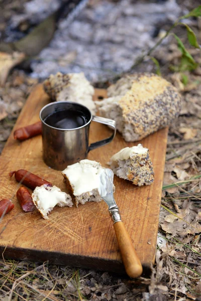 Gegrilde worstjes op snijplank in het bos — Stockfoto