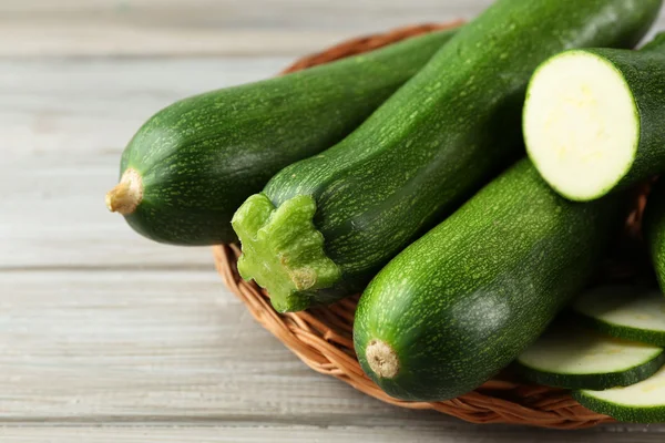 Frische Zucchini auf Weidenmatte auf Holzgrund — Stockfoto