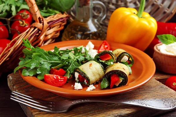 Zucchini rolls with cheese, bell peppers and arugula on plate, close-up, on table background — Stock Photo, Image