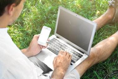 Adam yeşil çimenlerin üzerinde dizüstü bilgisayar ile    