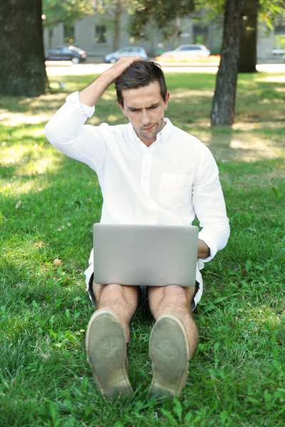 Uomo con computer portatile su erba verde — Foto Stock