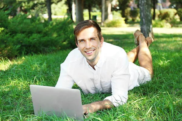 Homem com laptop na grama verde — Fotografia de Stock