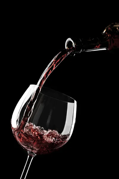 Pouring red wine from bottle into glass — Stock Photo, Image