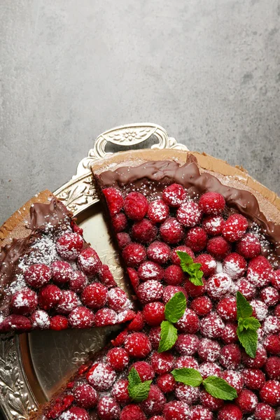Cake met chocolade glazuur en frambozen op lade op donkere achtergrond — Stockfoto