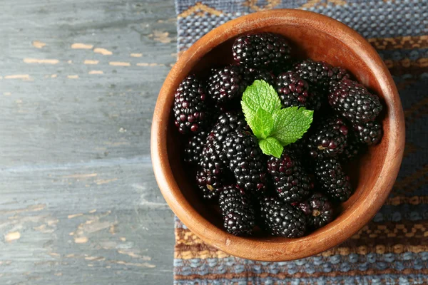 Rijp blackberry in kom op een houten achtergrond kleur — Stockfoto