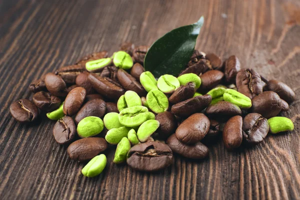 Зеленые и коричневые кофейные зёрна на деревянном фоне — стоковое фото