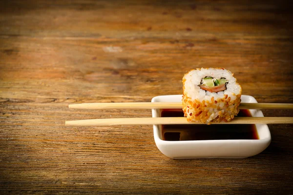 Rollo con salsa y palos en la mesa de madera de cerca —  Fotos de Stock