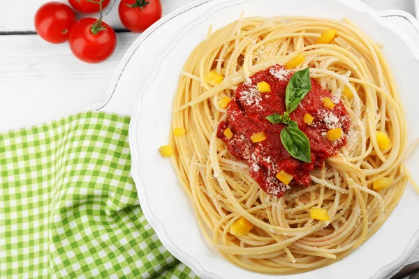 Spaghetti mit Tomatensauce und Käse auf weißem Teller, auf farbigem Holzhintergrund — Stockfoto