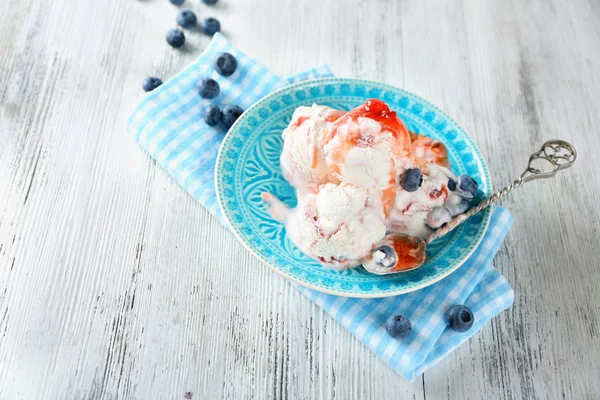 Leckeres Eis mit frischen gefrorenen Beeren und Soße, auf farbigem Holzhintergrund — Stockfoto