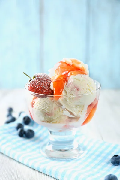 Delicioso sorvete com frutas frescas congeladas e molho, na cor de fundo de madeira — Fotografia de Stock