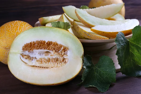 Melones maduros con hojas verdes sobre mesa de madera de cerca —  Fotos de Stock