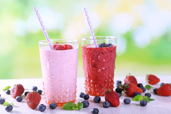 Glasses of berry smoothie on wooden table on blurred background — Stock Photo, Image