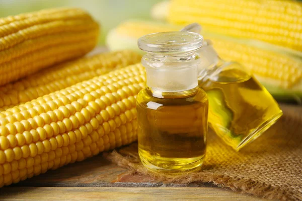 Fresh corn with bottles of oil on table close up — Stock Photo, Image