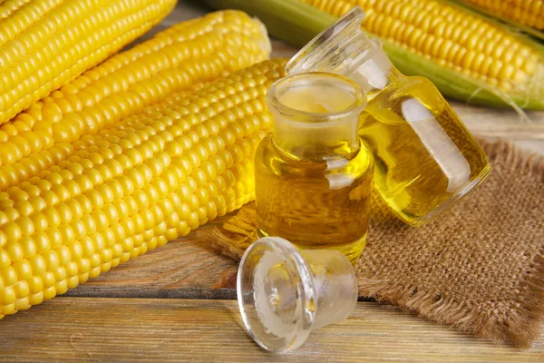 Fresh corn with bottles of oil on table close up — Stock Photo, Image