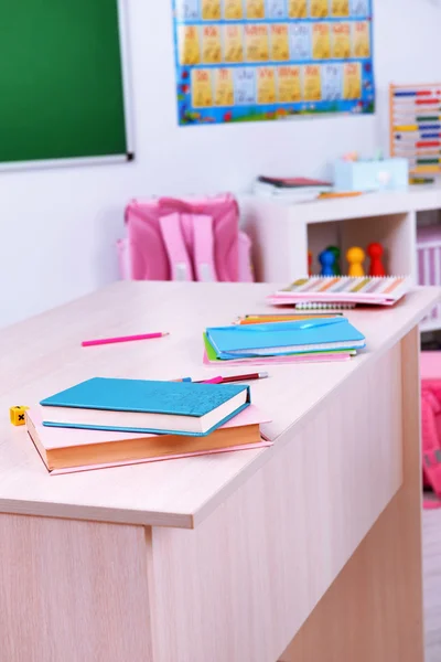 Desktop with books in classroom — Stock Photo, Image