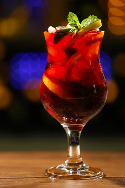 Glass of cocktail on dark blurred lights background — Stock Photo, Image