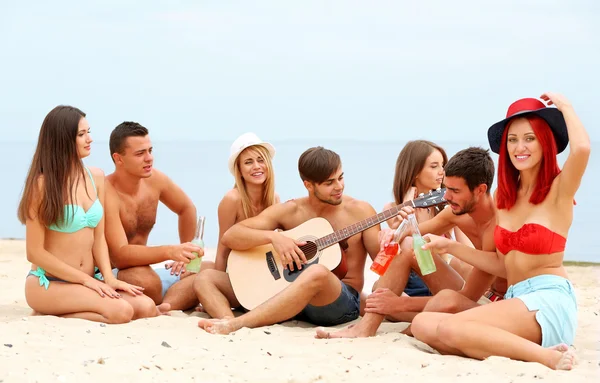 Schöne junge Leute mit Gitarre am Strand — Stockfoto