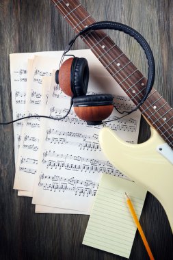 Elektro gitar nota ahşap zemin üzerinde ve kulaklık ile