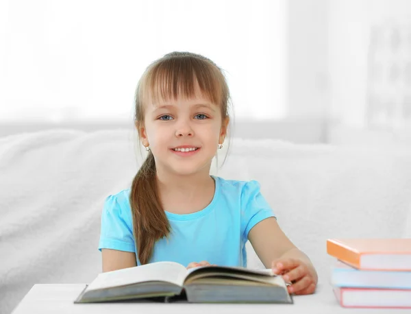 Bambina seduta sul divano con libro — Foto Stock