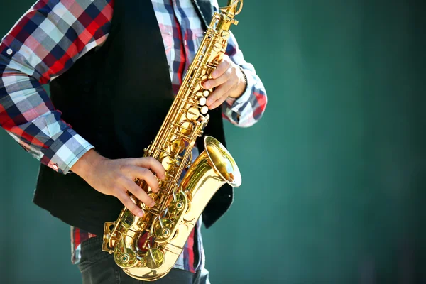 Jonge man spelen op saxofoon buiten in de buurt van de oude muur — Stockfoto