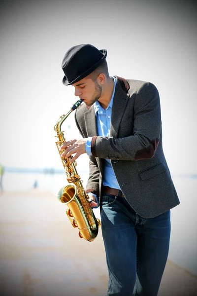 Joven tocando el saxofón a orillas del río —  Fotos de Stock